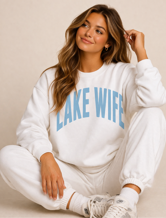 Woman wearing a white sweatshirt with 'LAKE WIFE' text on a beige background